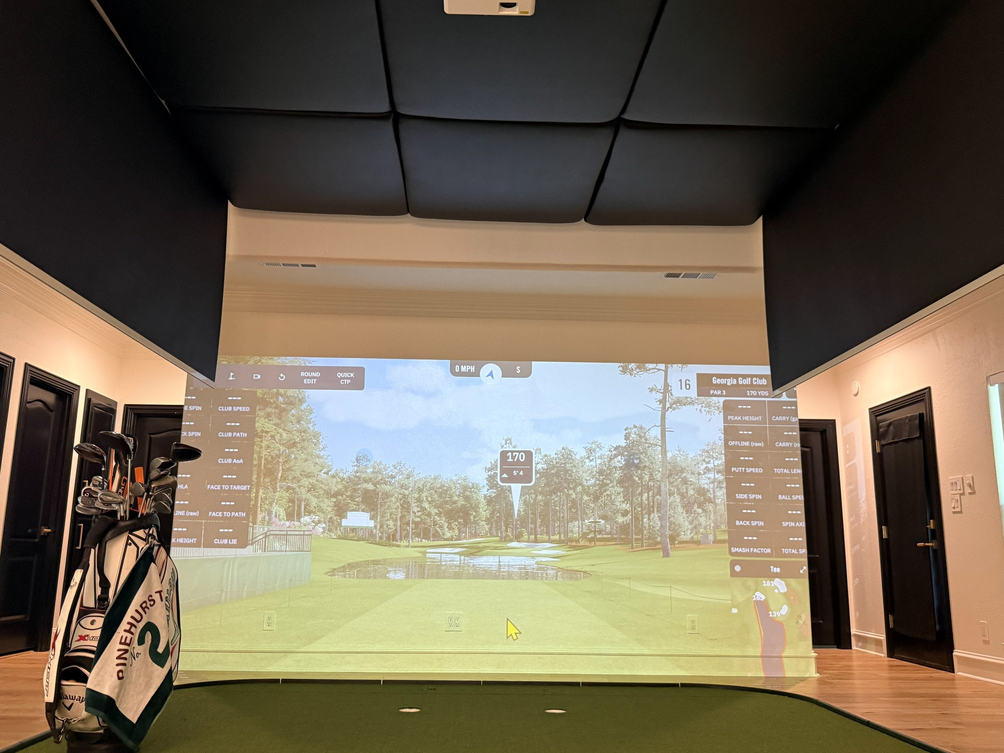 Wide view of a retractable golf simulator bay set up in a home garage