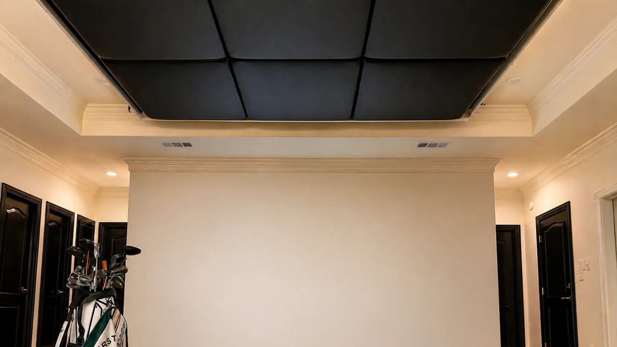 Golf simulator room with dark impact padding panels installed across the coffered ceiling